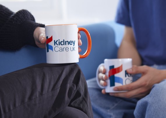 Patient and Kidney Care UK staff member, chatting over a cup of tea. Both of them are holding Kidney Care UK branded mugs.