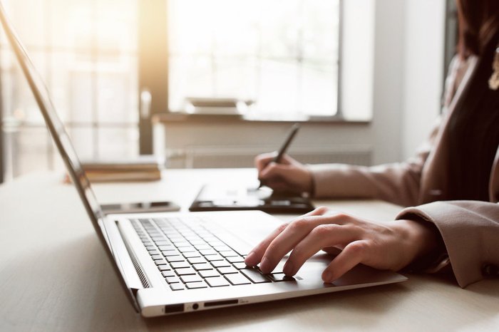 Person looking at laptop and writing notes