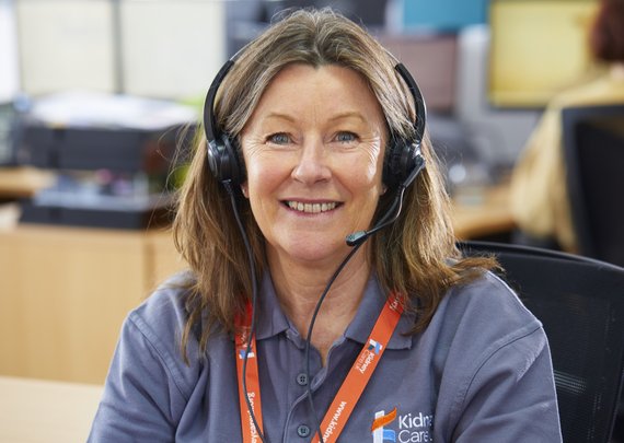 Kidney Care UK Support Line staff smiling for a photo in the Kidney Care UK office. She is wearing branded polo shirt and lanyard.