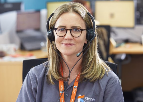 Kidney Care UK Support Line staff smiling for a photo in the Kidney Care UK office. She is wearing branded polo shirt and lanyard.