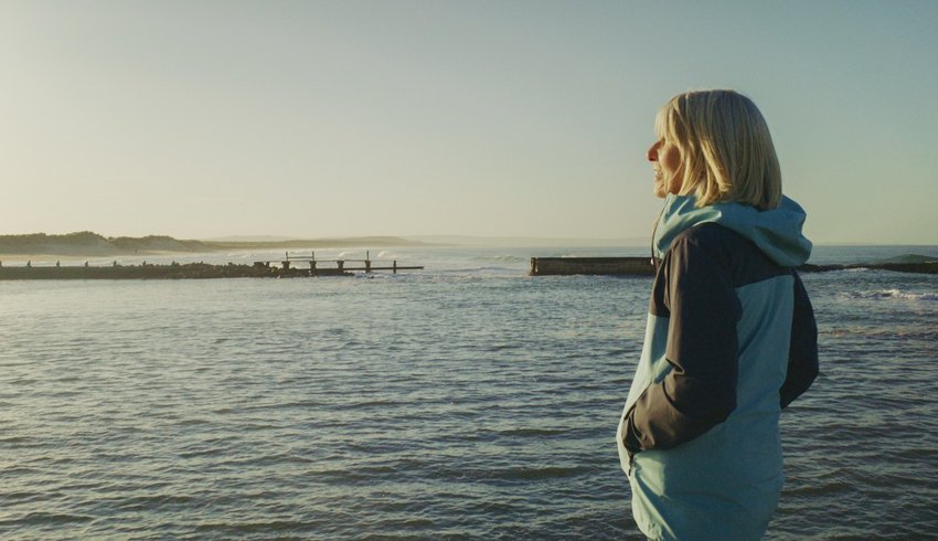 Woman walking on the coast in Scotland and looking out to sea.